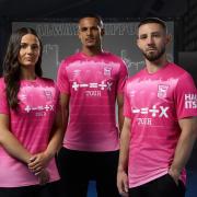 Maria Boswell, Ali Al-Hamadi and Conor Chaplin model Ipswich Town's pink third shirt.